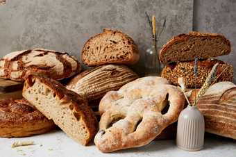 A selection of various artisan breads, some cut in half, against a white background.