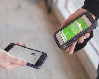 A close up of a member of staff scanning an exhibition ticket on a mobile phone.