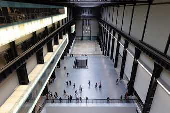 an birds eye view of people standing and walking around the Turbine Hall, a big entrance space in Tate Modern